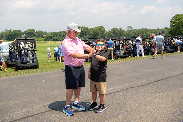 Golf Invitational Chair and Champion Child share high five