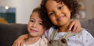 Young siblings with arms over each others shoulders