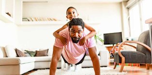 Man doing push ups with child on his back