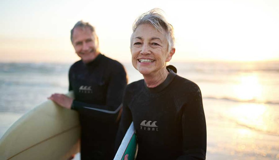 Older women and man surfing on beach