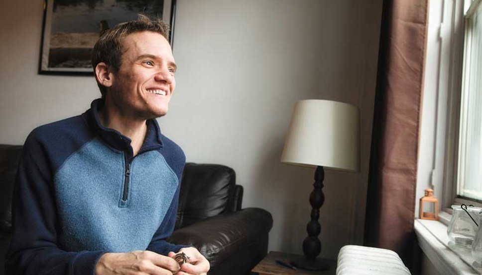 Young adult man smiling looking out window