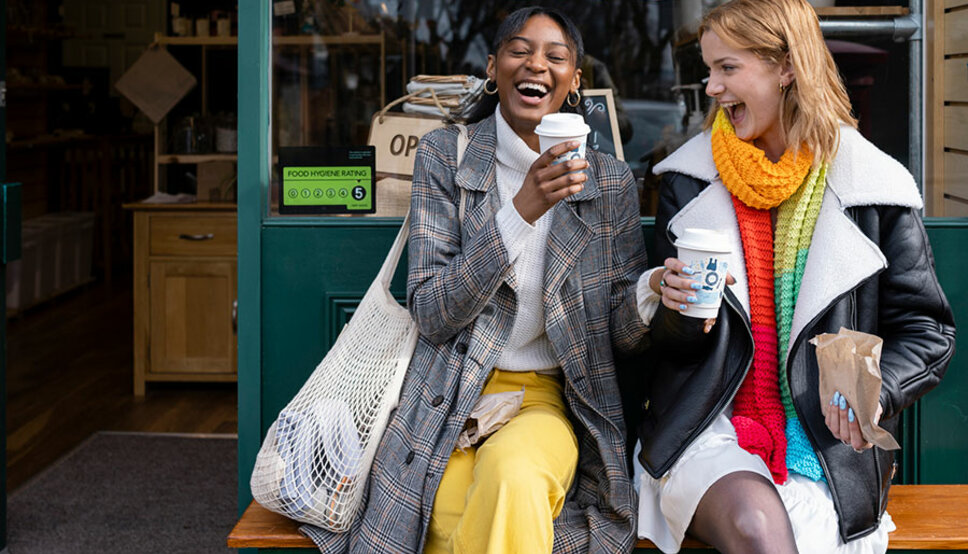 Two young adults laughing outside cafe