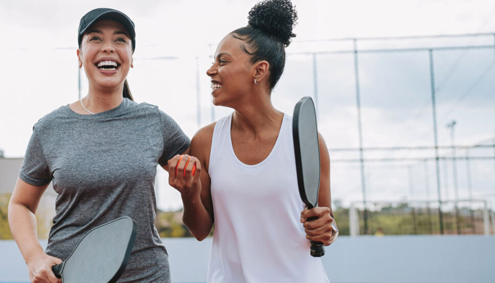 Two women playing laughing after playing pickleball