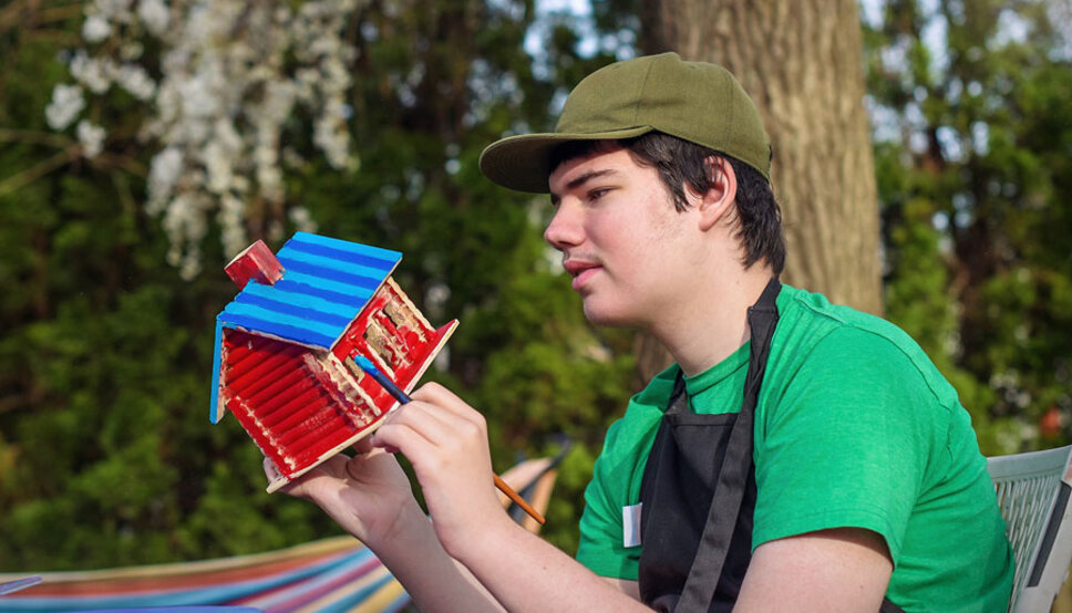 Teenager with autism outside doing a painting craft