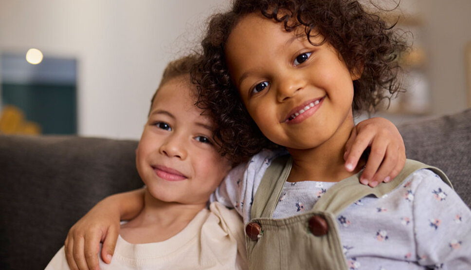 Young siblings with arms over each others shoulders