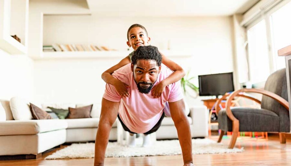 Man doing push ups with child on his back