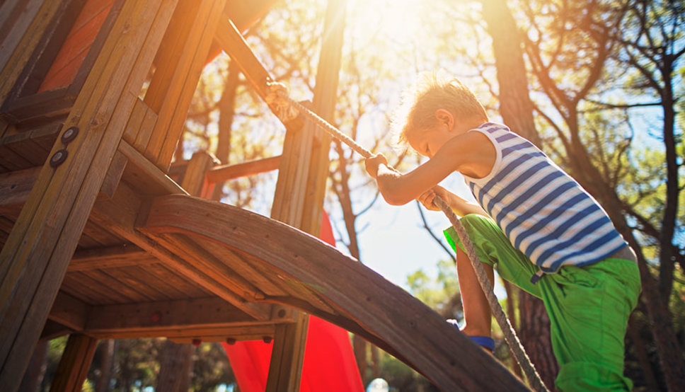 Young child climbing up a rope on playground equipment