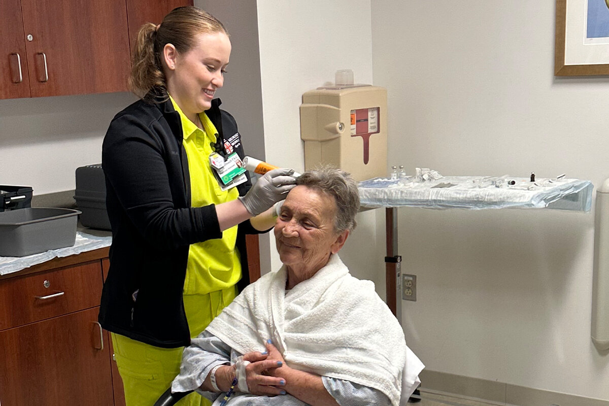A technician shaves Rita Dennis's scalp.