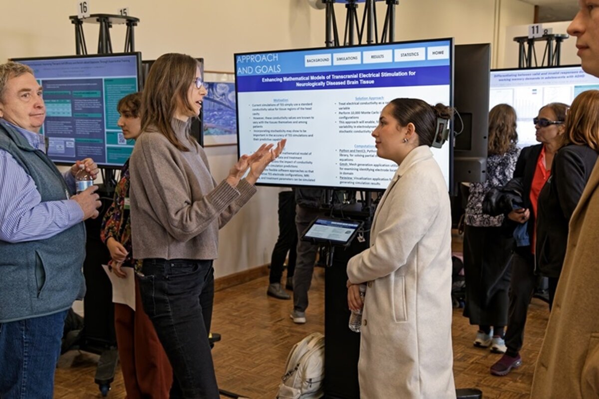 Attendee discusses poster with woman in lab coat
