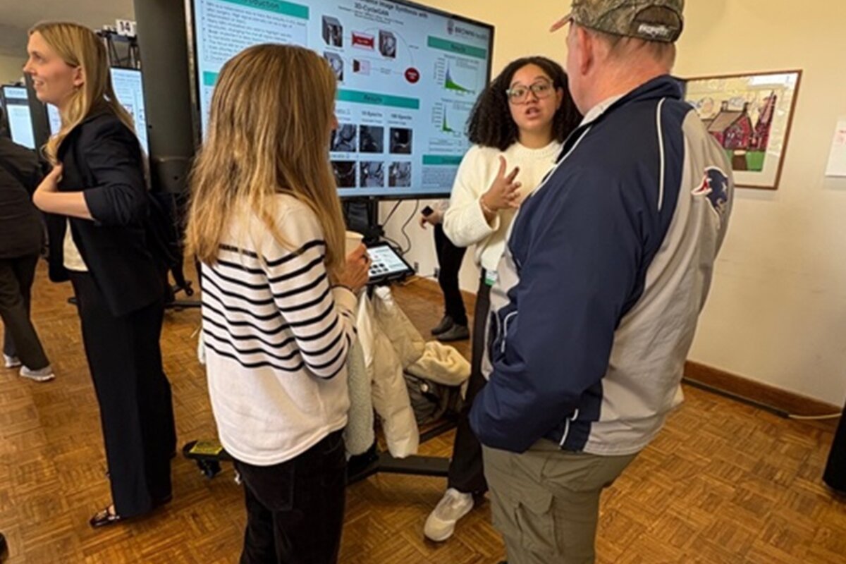 Three attendees discuss a digital poster