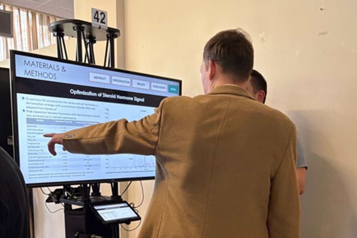 Two attendees discuss digital poster and one points