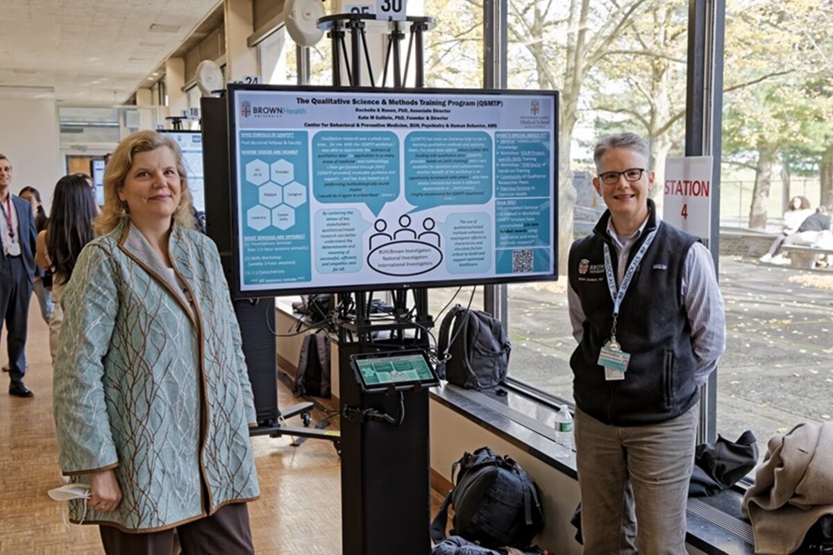 Two attendees face camera in front of poster