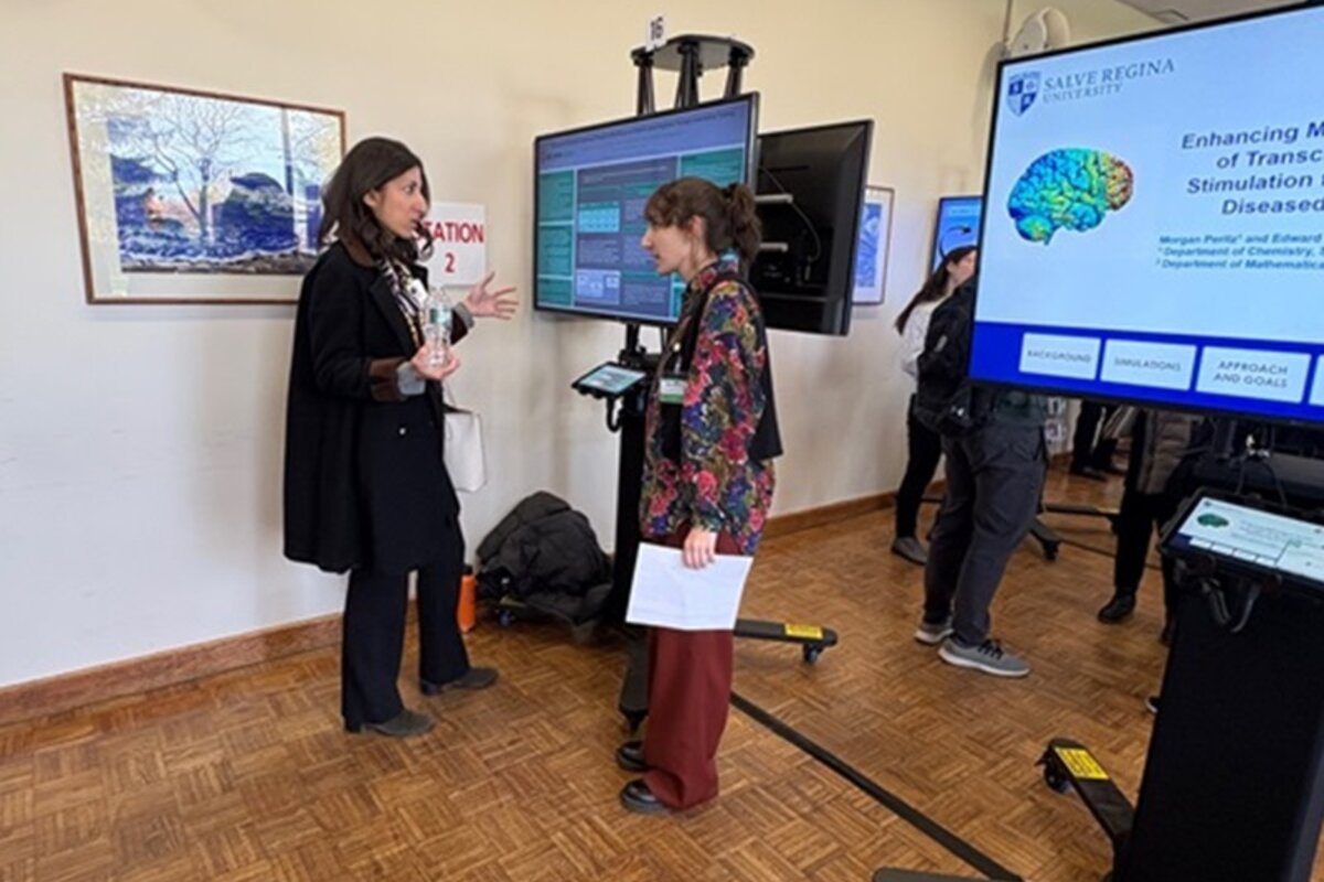 Two attendees talk next to corner poster