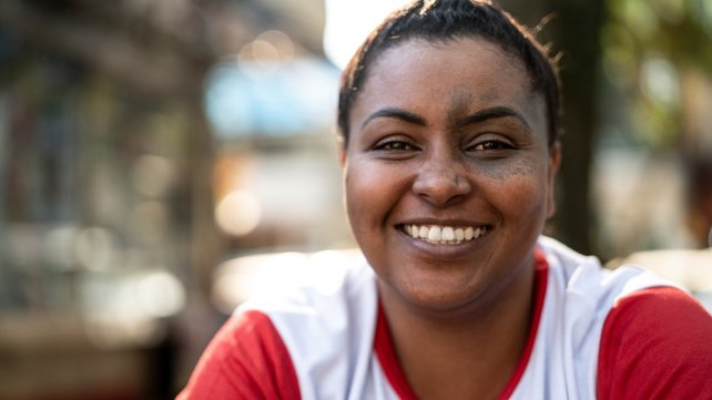 Woman smiling at camera with city sidewalk in the background