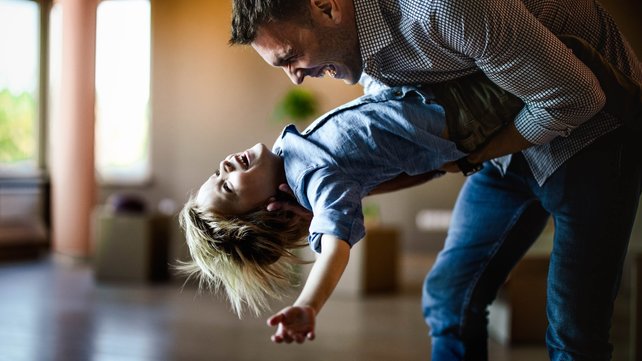 Man playing with young child in living room