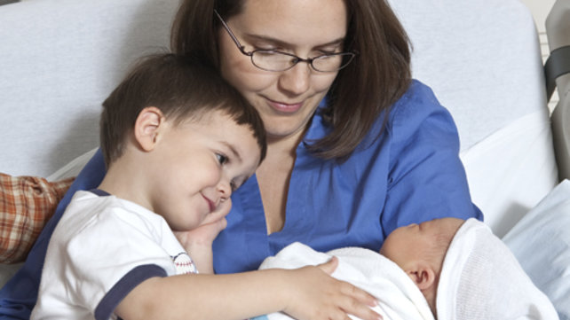 A woman and small child hold a newborn.