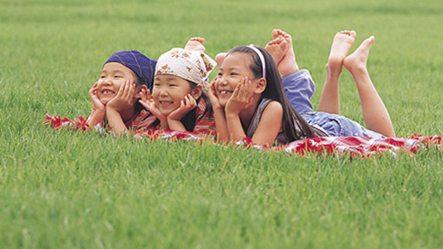 three children outside on a blanket