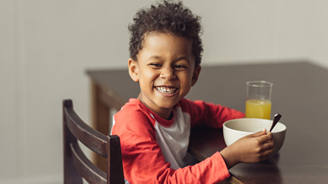 little boy smiling while eating cereal