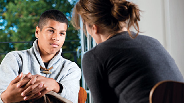 teenager in grey sweater sitting with adult