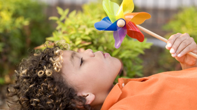 child blowing on pinwheel