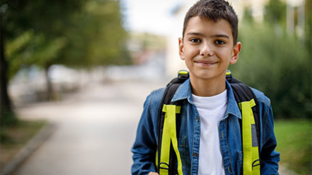 Child wearing a backpack walking down a road