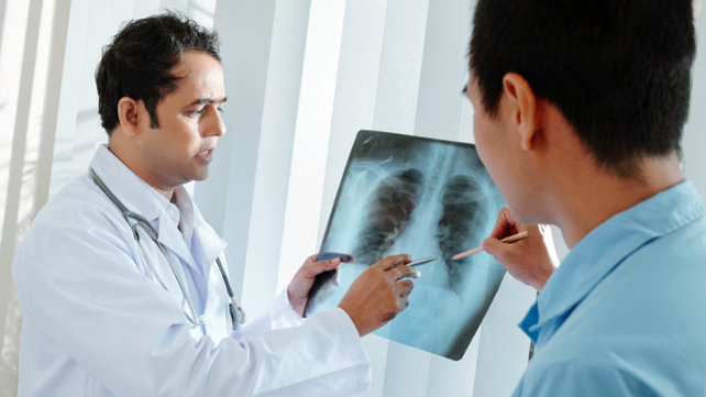 A doctor and a patient looking at an x-ray of lungs.