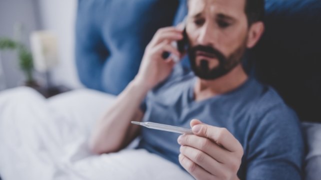 man with thermometer on the phone