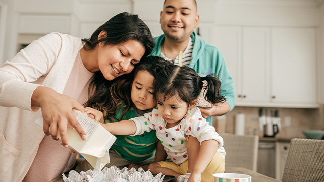 Two adults and two children doing a craft project.