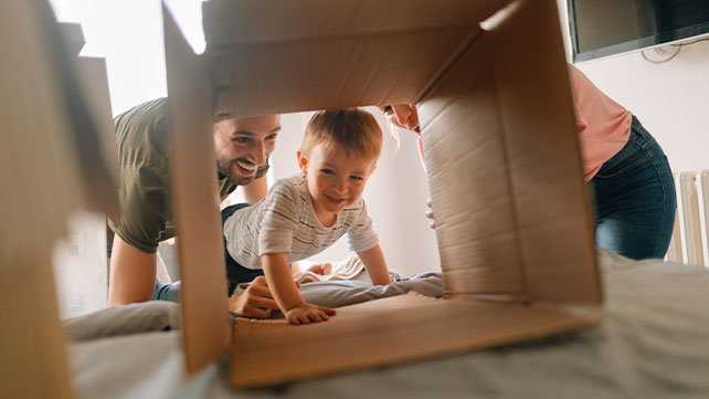 Two adults play with a crawling toddler.