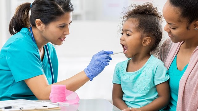 Young child having her throat looked at by a doctor
