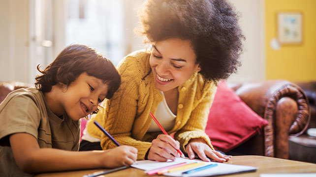 An adult and child working at a desk.