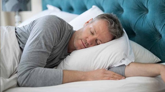 adult male sleeping on a pillow in bed