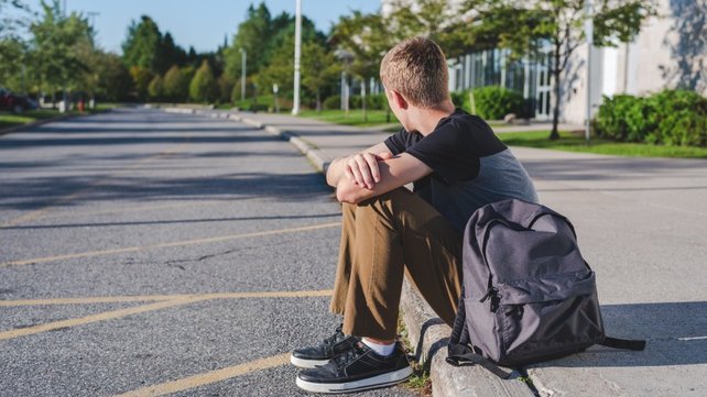 young boy sitting alone on a curb