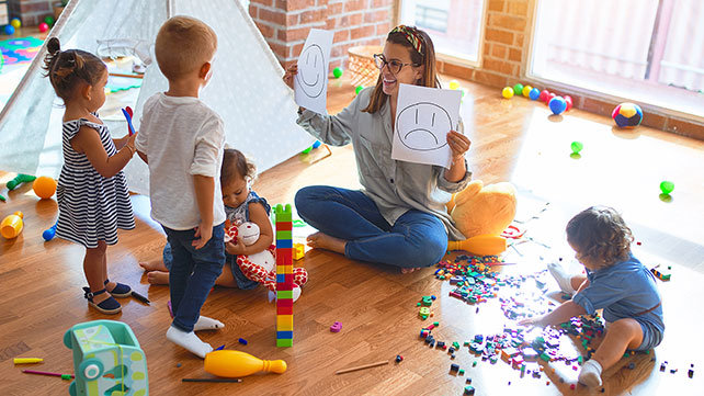 Teacher showing children difference between happy and sad faces.