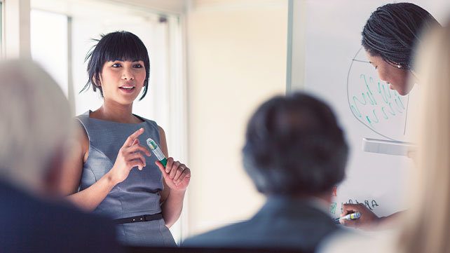 Woman in blue dress presenting to na audience