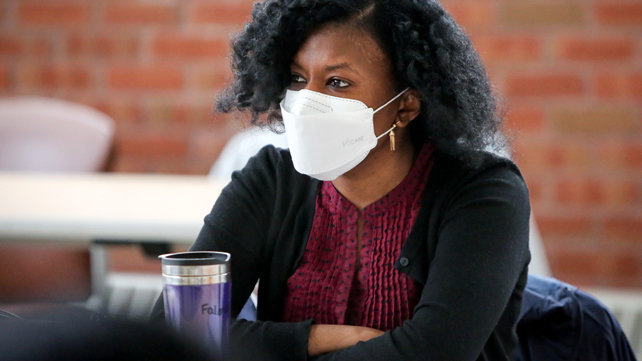 A woman of color, wearing a mask, sitting at a career training session