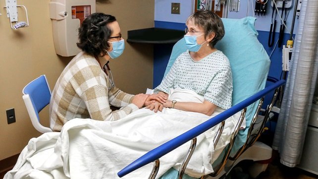 Leah McDonald, MD, a palliative care physician, providing comfort through conversaton with an older female patient in the emergency department at The Miriam Hospital.