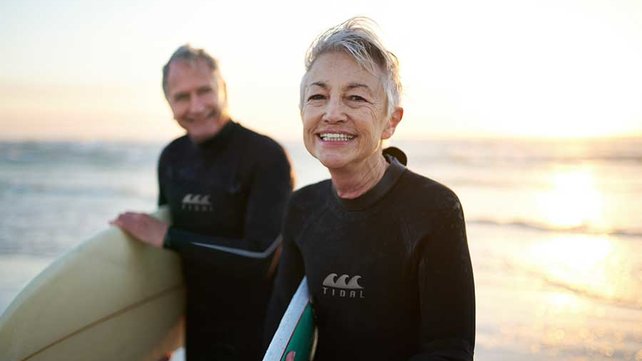 Older women and man surfing on beach