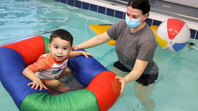 A child getting rehab in a pool with a therapist.