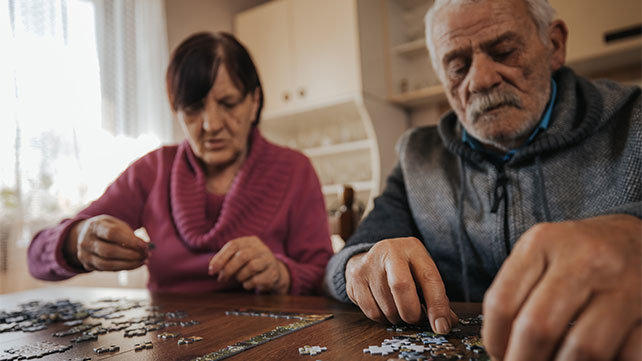 An older couple working on a jigsaw puzzle.
