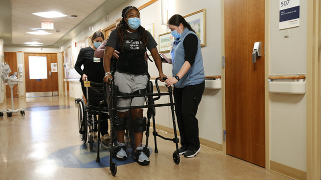 A patient walks while wearing an exoskeleton