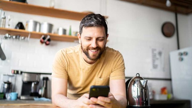 Man looking at phone in kitchen