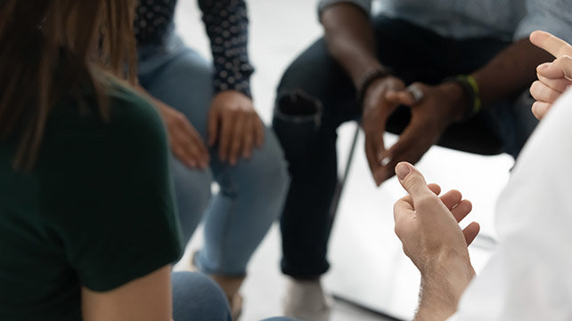 A groupf of adults sitting in a circle and talking