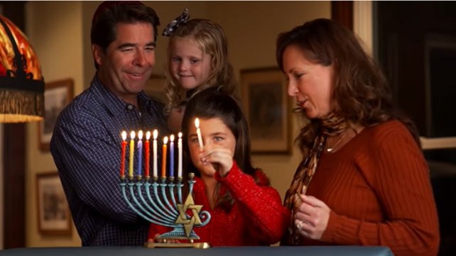 Mother, father, and children lighting a menorah