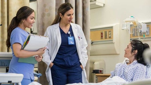  A female hospitalist taking care of a patient in a hospital bed