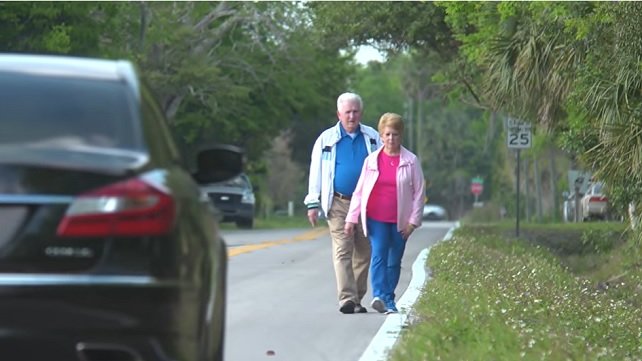Older couple walking safely along the side of a road