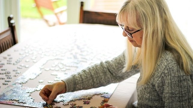 Woman sitting at a table and putting together a puzzle