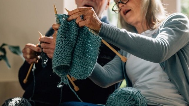 Older woman sitting in her living room and knitting