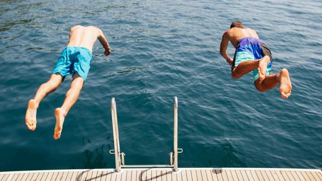 Two boys diving into water from dock
