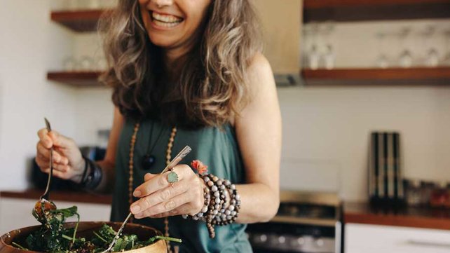 Women making salad and smiling